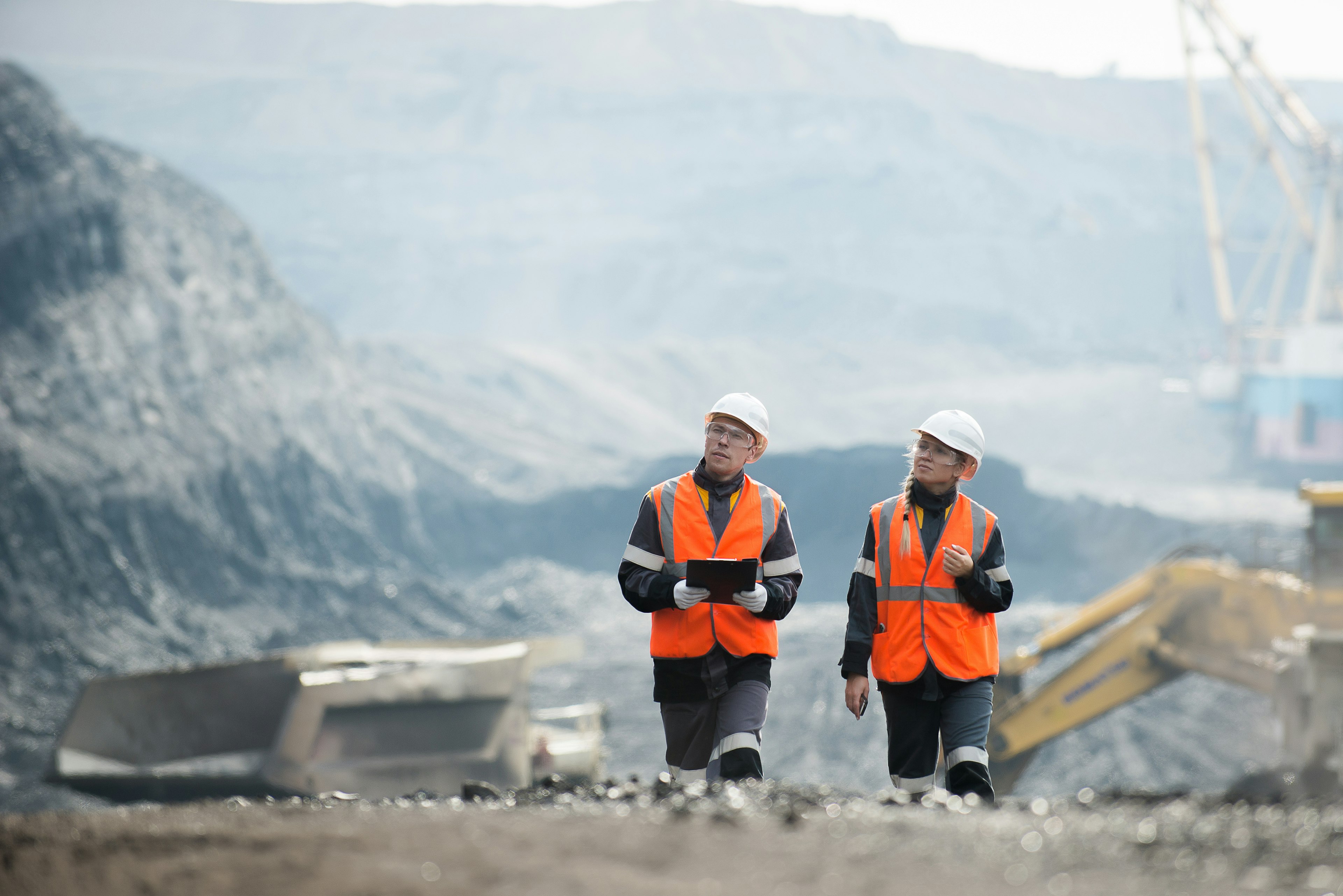 Workers walking a mining site managing mining automation tools on a tablet device